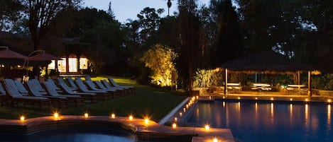 Una piscina al aire libre, sombrillas, sillones reclinables de piscina