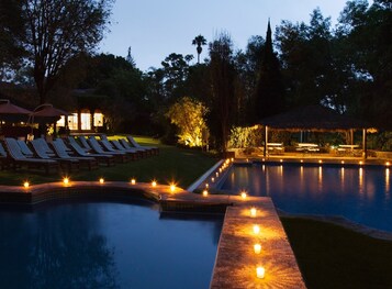 Una piscina al aire libre, sombrillas, sillones reclinables de piscina