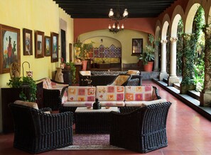 Un rincón tranquilo con muebles de mimbre, suelo de baldosas y un techo decorativo.