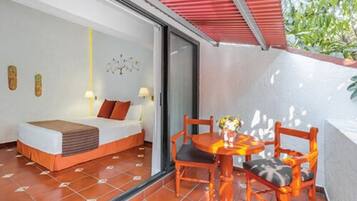 Habitación de hotel con cama, una mesa y sillas, y vista a zonas verdes.