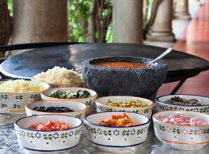 A table with various bowls of food and a stone mortar with a spoon.