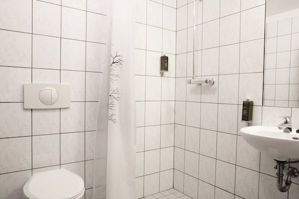 A bathroom with a toilet, a shower, and a sink.