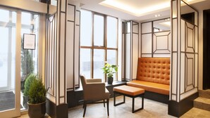 A modern lobby with a seating area, large windows, and a potted plant. - Fosshotel Barón (Reykjavik)