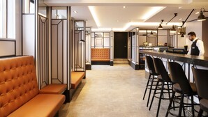 A modern kitchen with a bar area, seating, and a view into the dining area. - Fosshotel Barón (Reykjavik)