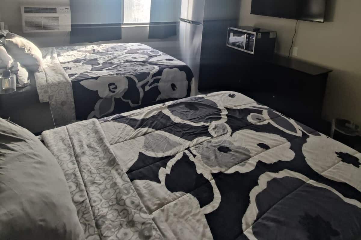 Habitación de hotel con dos camas, televisión de pantalla plana, refrigerador y aire acondicionado.