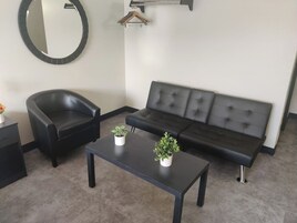 Un salon moderne avec un canapé en cuir noir, un fauteuil noir et une table basse agrémentée de deux plantes en pot.