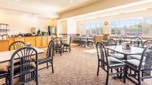 A dining area with tables and chairs, a kitchen area with appliances, and large windows with a view.