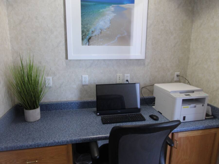 A home office with a desk, computer, printer, and a framed picture of a beach.