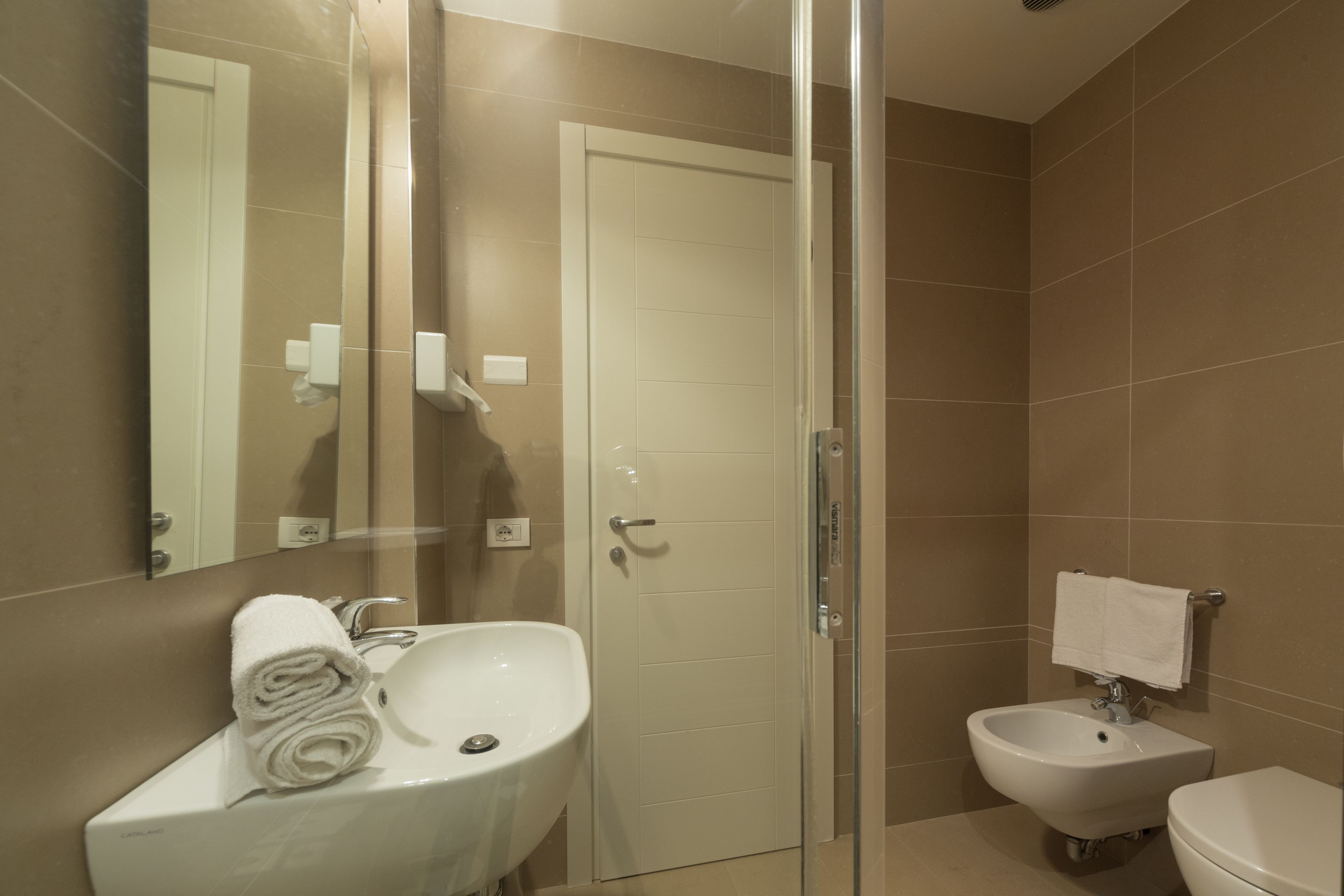 Un bagno moderno con cabina doccia in vetro, lavandino bianco, bidet e water.