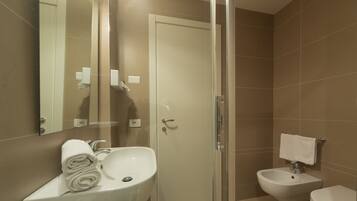 Un bagno moderno con cabina doccia in vetro, lavandino bianco, bidet e water.