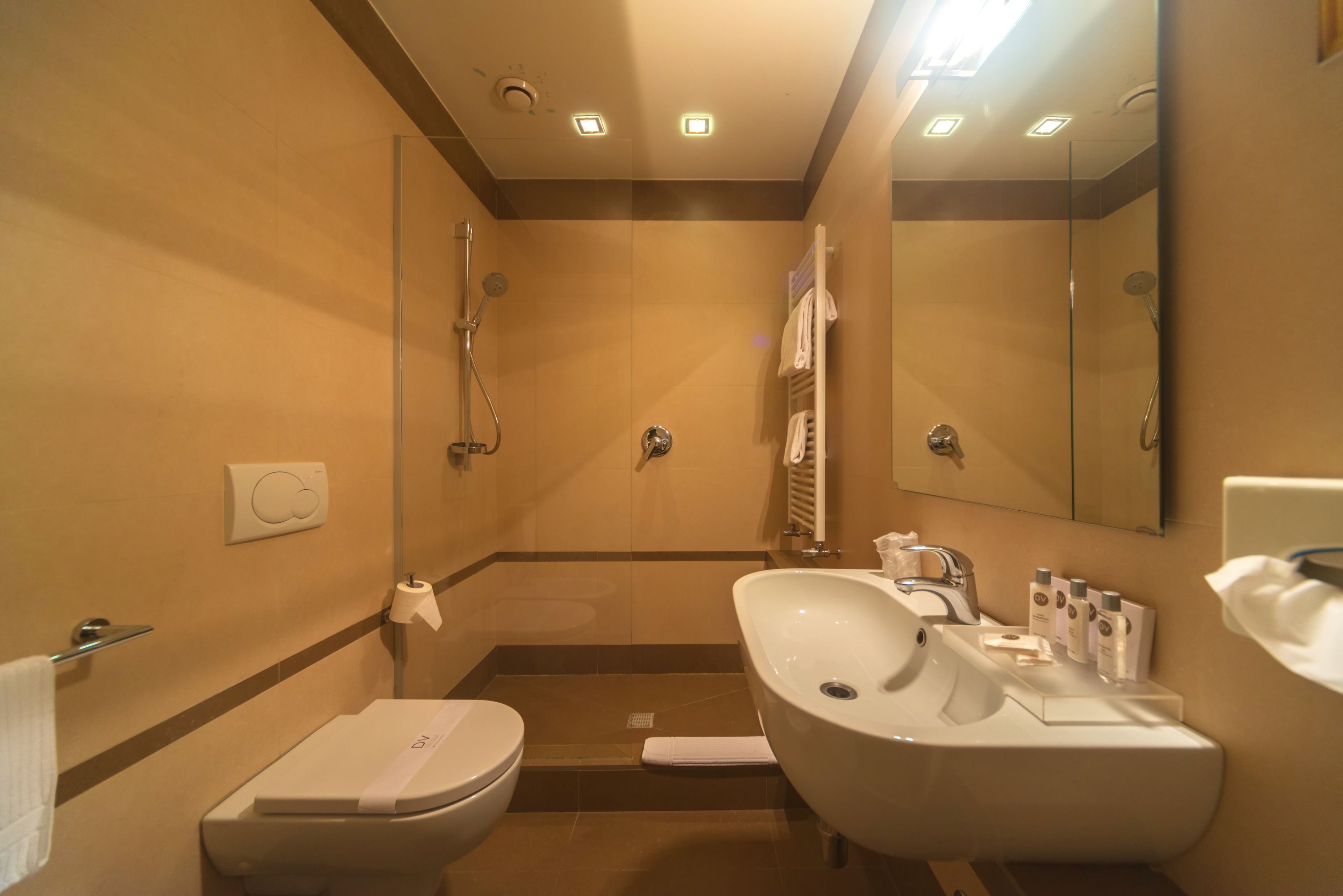 A bathroom with a toilet, bidet, and sink, equipped with a towel rack and a mirror.