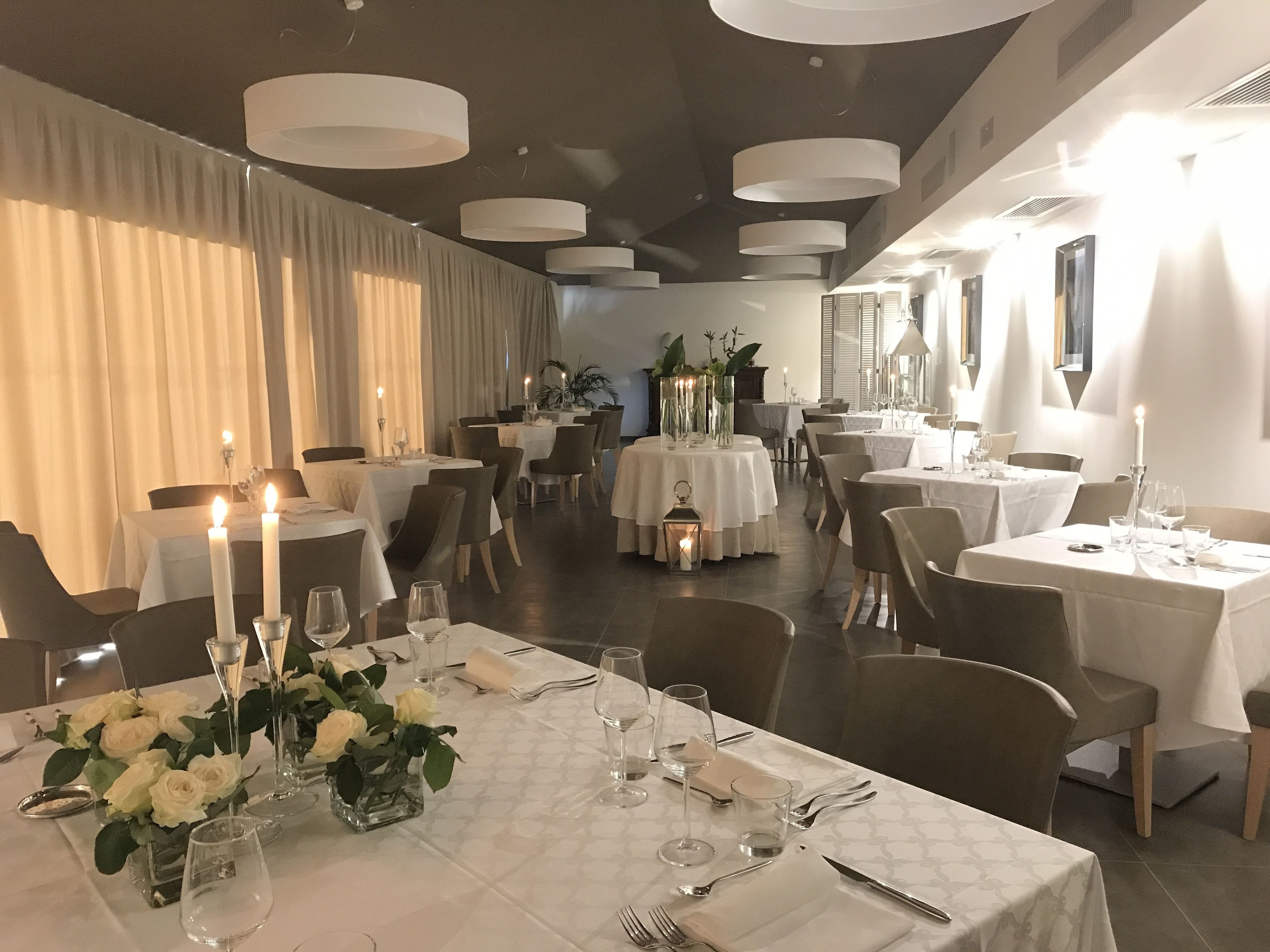 Un restaurante con mesas redondas, velas y manteles blancos.