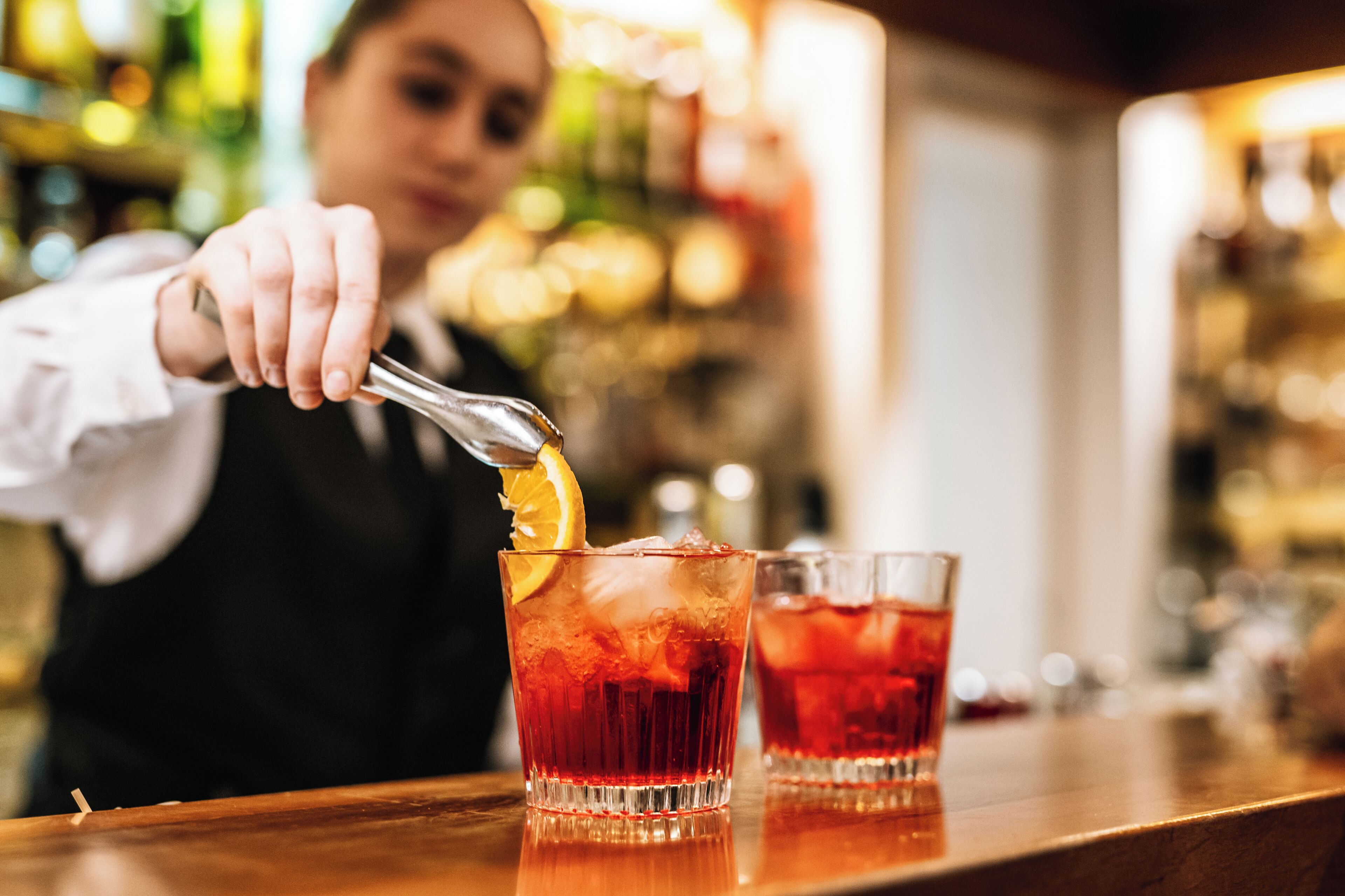 A bartender preparing a drink with a citrus garnish.