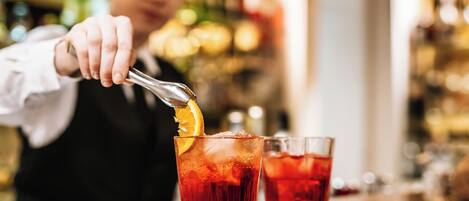 A bartender preparing a drink with a citrus garnish.