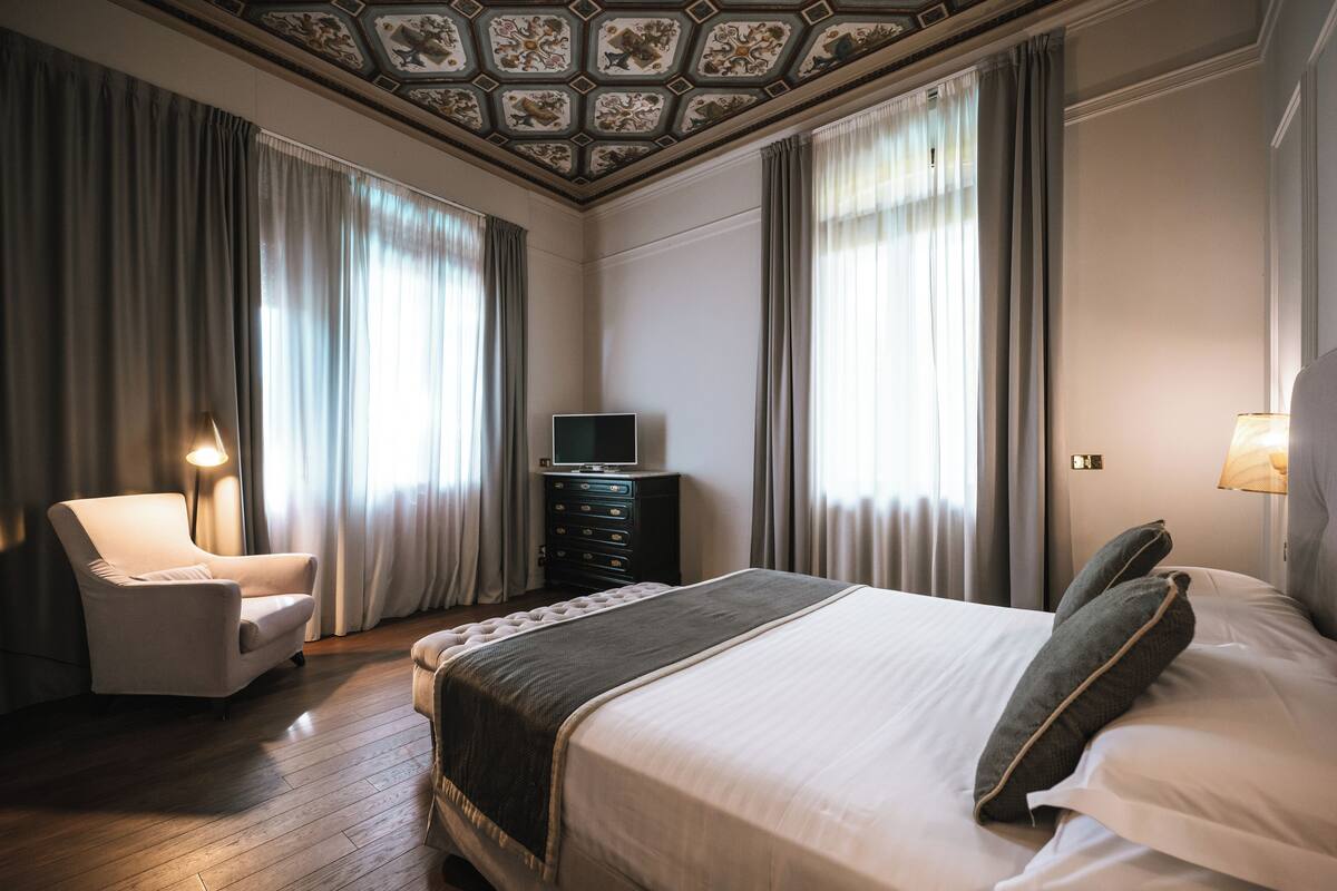 Een hotelkamer met een groot bed, een stoel, een dressoir en een televisie.