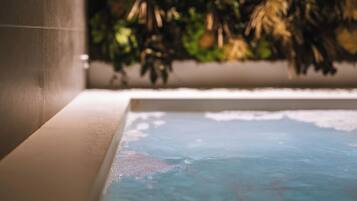 Una bañera con vista a un muro verde.