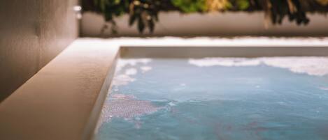 A bathtub with a view of a plant wall.