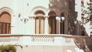 A poolside area with lounge chairs and a building with classical architecture.