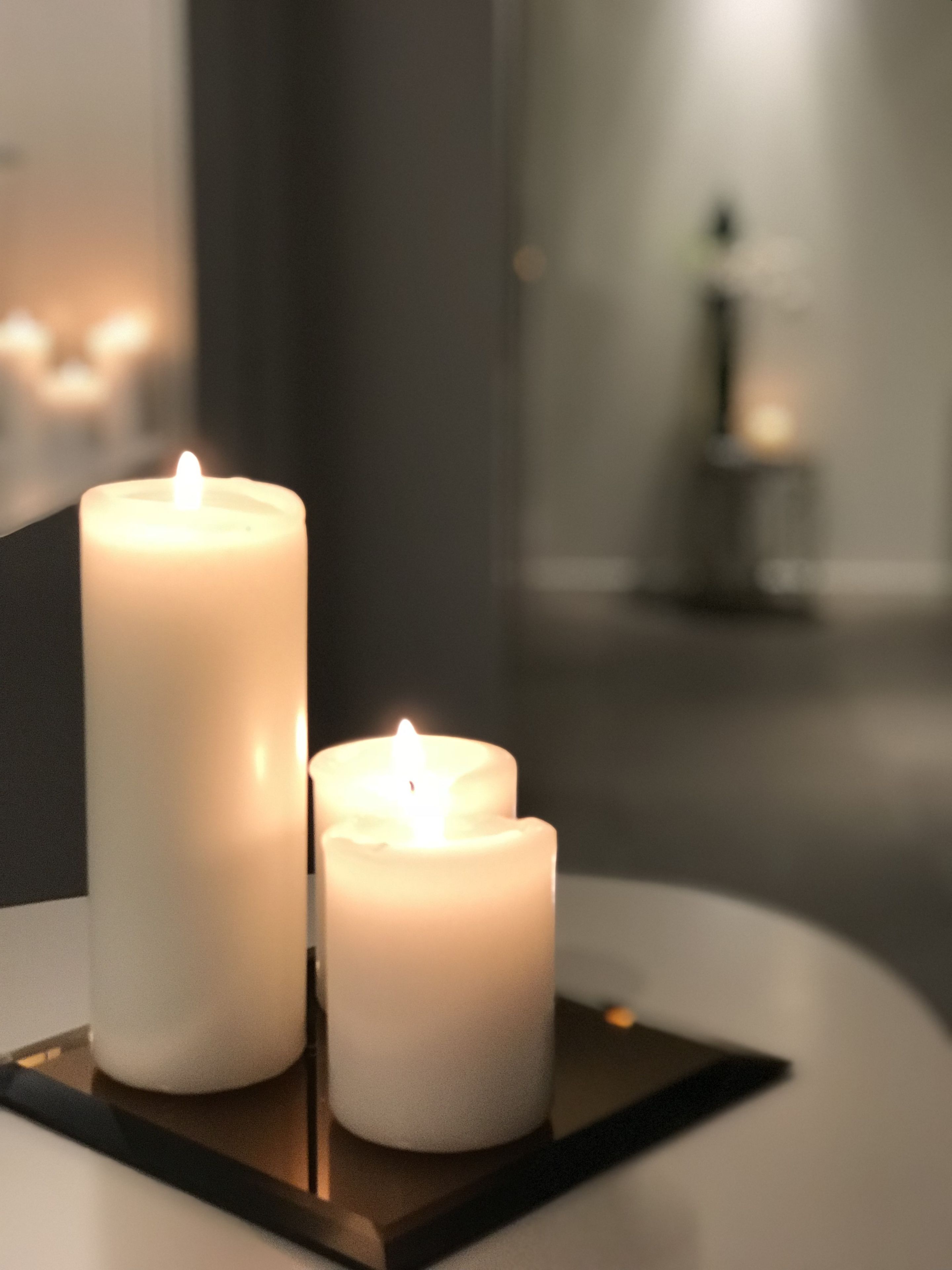 Three white candles on a black tray.