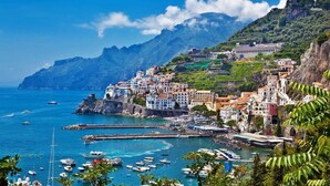 A coastal town with buildings on a hillside, a marina with boats, and a clear blue sea. - Ravello Art Hotel Marmorata (Ravello)