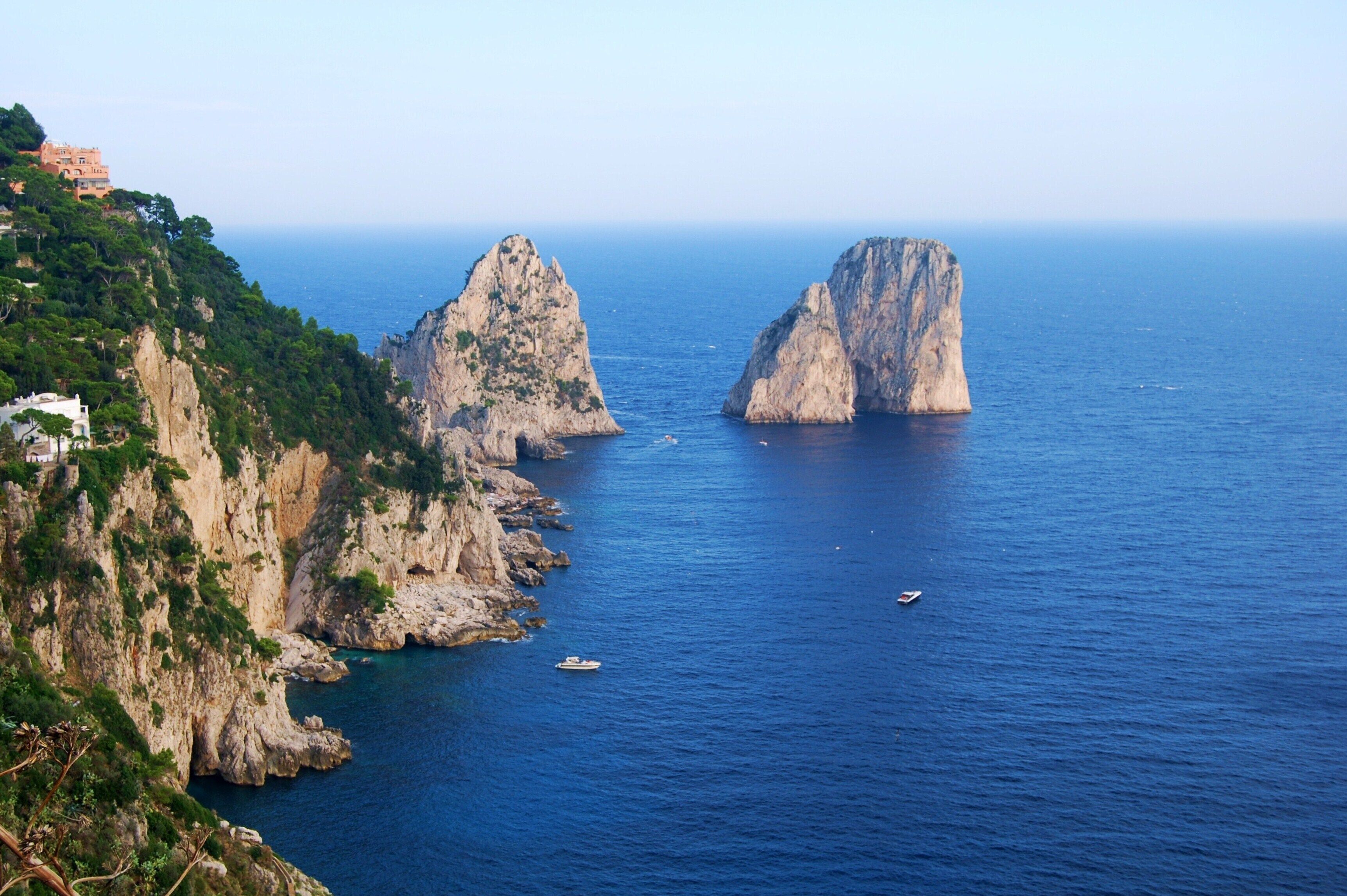 A coastal landscape with rocky cliffs and a clear blue sea.