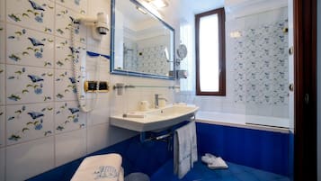 A bathroom with a white sink, blue tiles, a mirror, and a shower area.