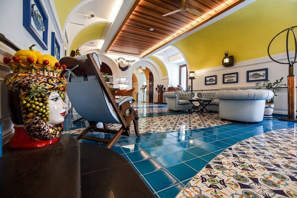 A spacious lobby with a tiled floor, a wooden ceiling, and a seating area with a sofa and armchairs. - Ravello Art Hotel Marmorata (Ravello)
