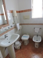 Un bagno con lavandino, WC, bidet e uno specchio.