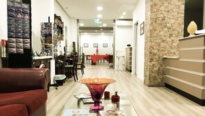 Un lobby moderno de hotel con una mesa de centro de vidrio, un sofá rojo y una pared de acento de piedra.