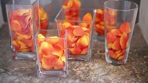 Four clear glass vases with rose petals on a granite countertop. - Hotel Charleston (Spoleto)