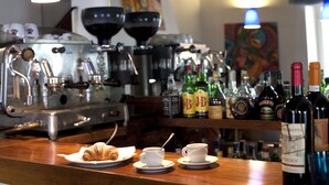A bar area with espresso machines, a croissant, and coffee cups on the counter. - Hotel Charleston (Spoleto)