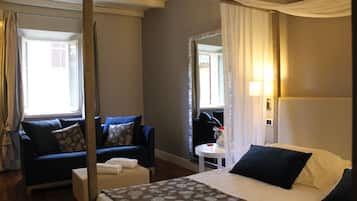 A hotel room with a bed, a sofa, a small table, and a mirror.