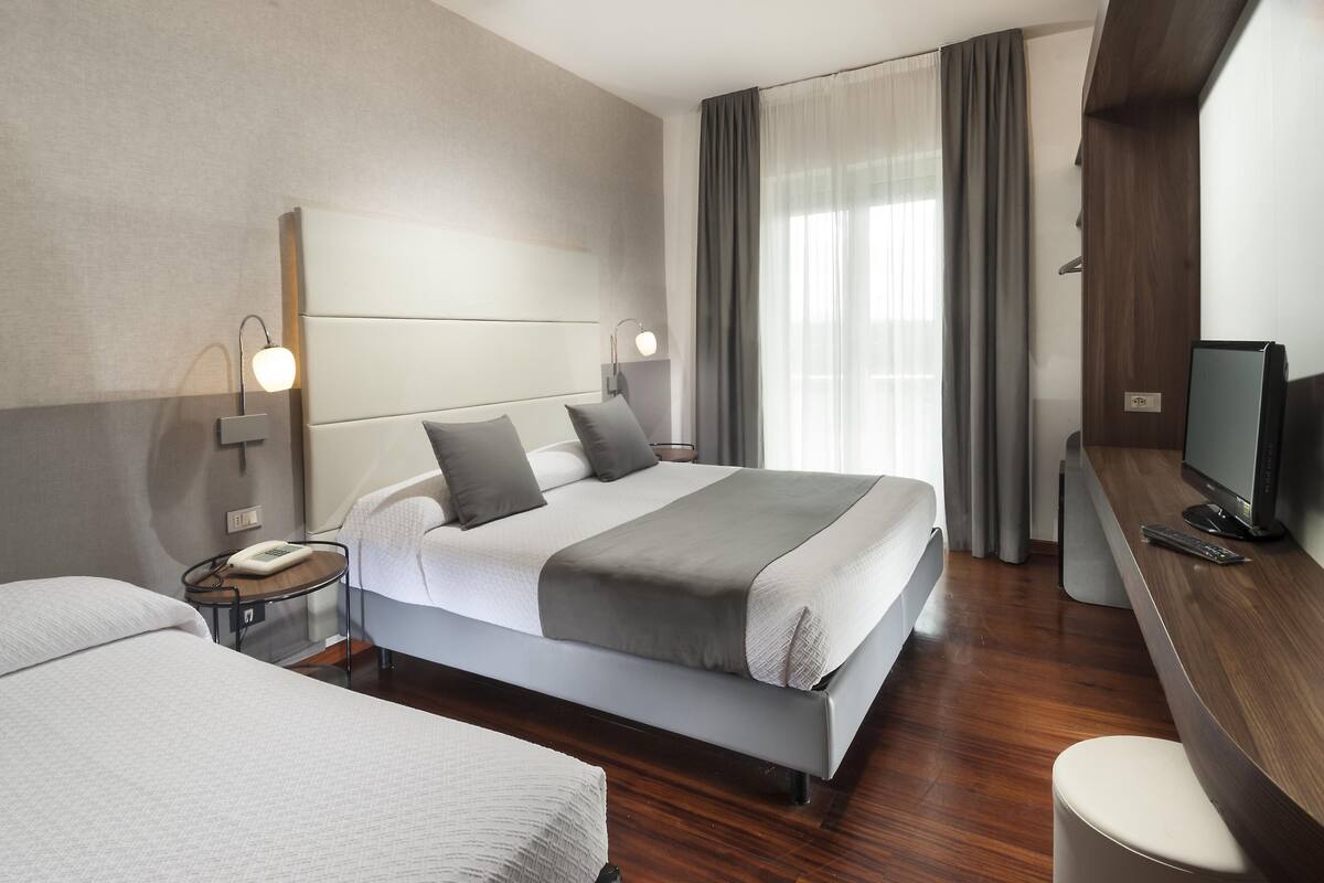 Ein modernes Hotelzimmer mit einem großen Bett, Nachttischen, einem Fernseher und einem Schreibtisch.