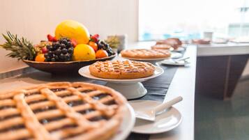 Una mesa de buffet con varios pasteles y un tazón de fruta.