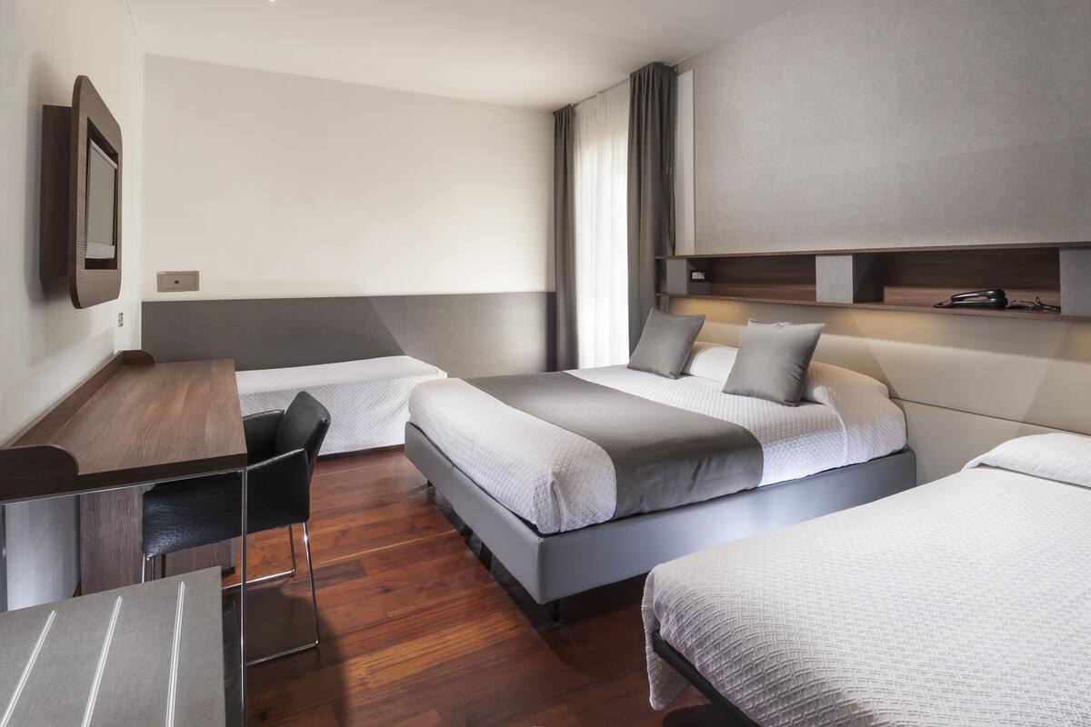 Ein Hotelzimmer mit zwei Betten, einem Schreibtisch und einem Sessel.