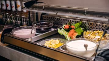 A buffet with various food items including a bowl of soup, a dish with lemon slices, and a container of yogurt.