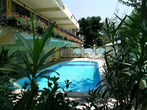 Una piscina al aire libre, sombrillas, sillones reclinables de piscina