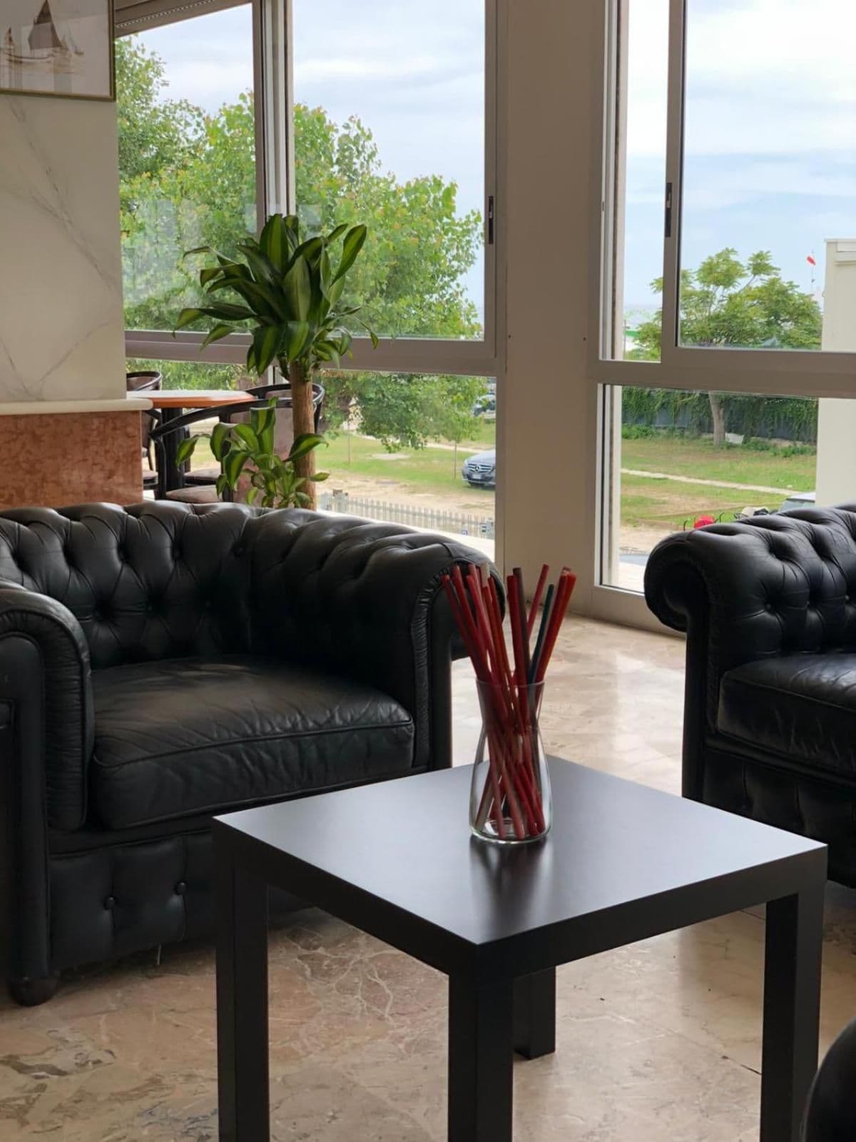 A spacious room with a leather sofa, a small table, and a large window offering a view of the outdoors.