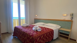 A hotel room with a bed, a nightstand, a wall-mounted phone, and a window with curtains. - Hotel Artide (Rimini)