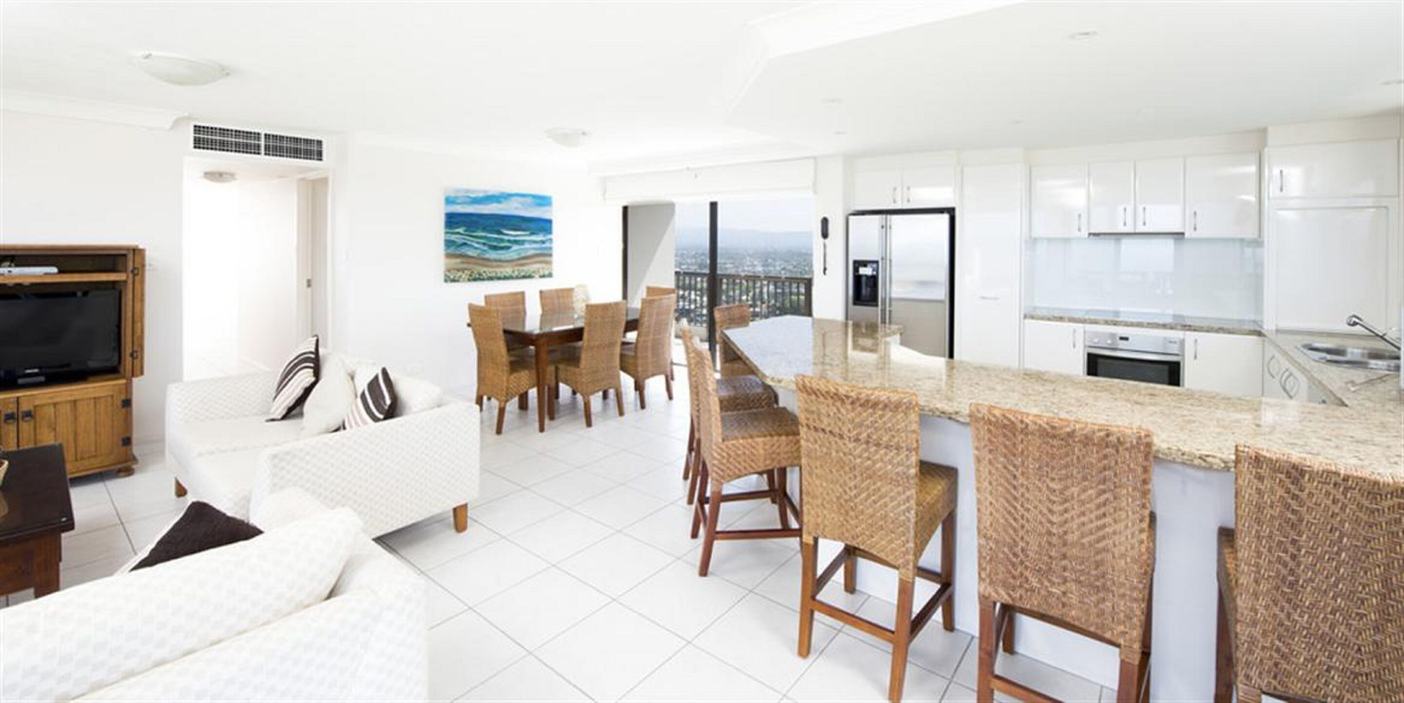 A modern kitchen with white cabinets, a built-in oven, and a large island with bar stools.