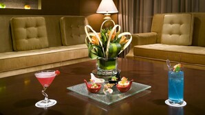 A dining table with a floral centerpiece, two cocktails, and small dishes of food. - Baolong Hotel Shanghai (Shanghai)