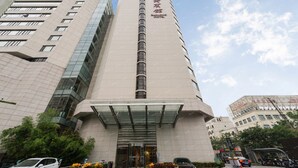 A tall hotel building with a modern facade, large windows, and a prominent entrance with a glass canopy. - Baolong Hotel Shanghai (Shanghai)