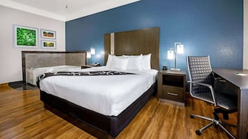 Habitación de hotel con una cama grande, un escritorio con silla, una mesita de noche y lámparas de pared.