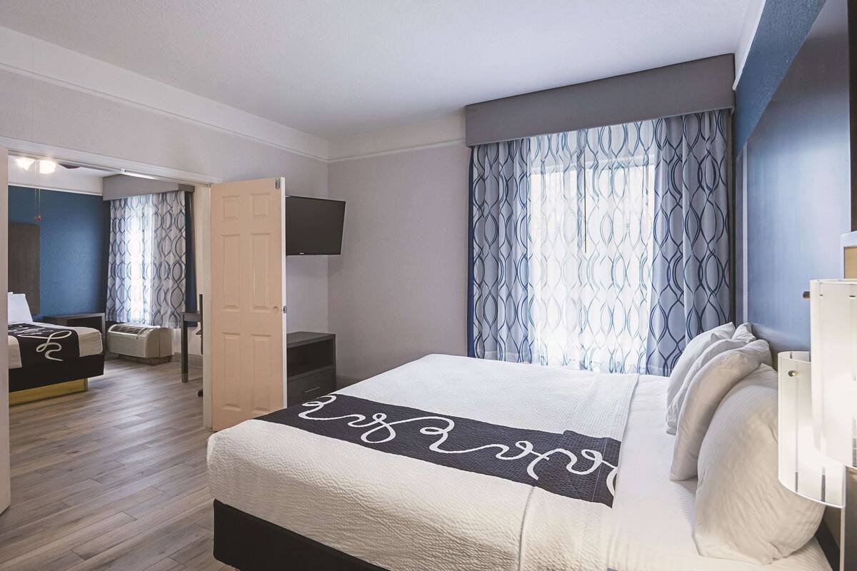 A hotel room with a bed, a TV mounted on the wall, a desk, and a chair.