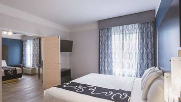 Een hotelkamer met een bed, een aan de muur bevestigde televisie, een bureau en een stoel.