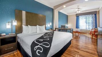 Ett hotellrum med en stor säng, sängbord, ett skrivbord och en stol.