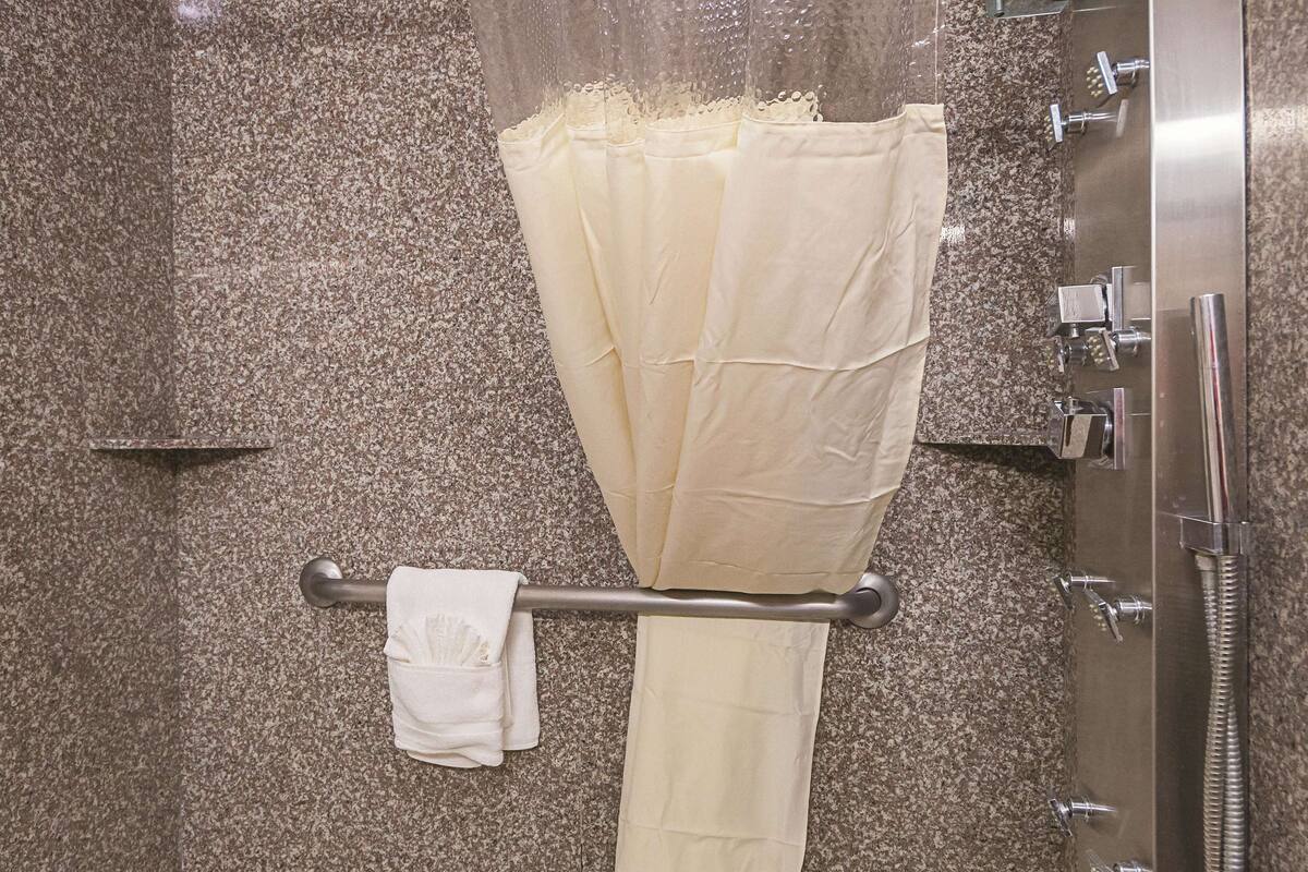 A bathroom with a shower curtain, towel rack, and a bathtub.