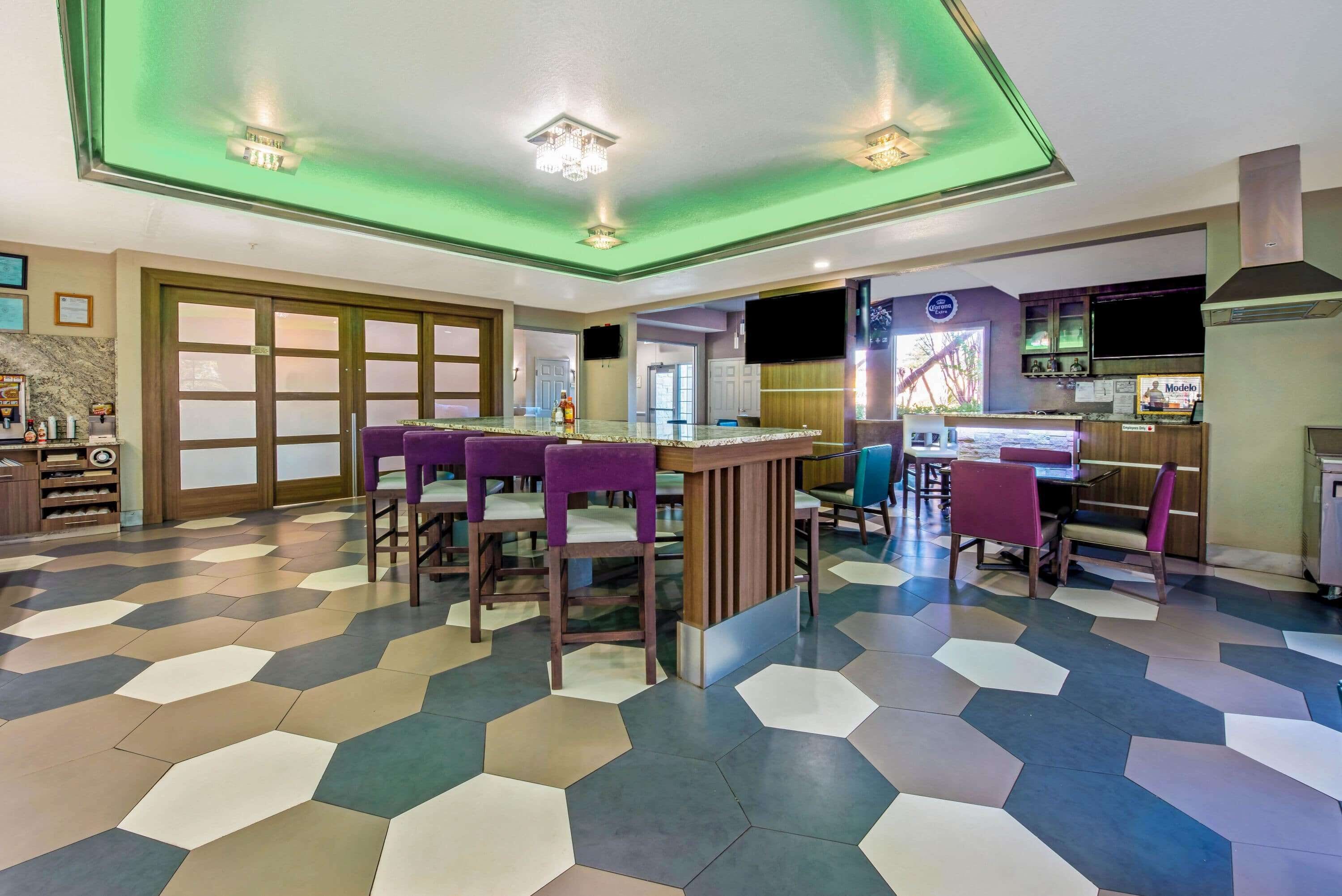 Una cocina moderna con una isla grande, asientos tipo bar y una zona de comedor con piso estampado.