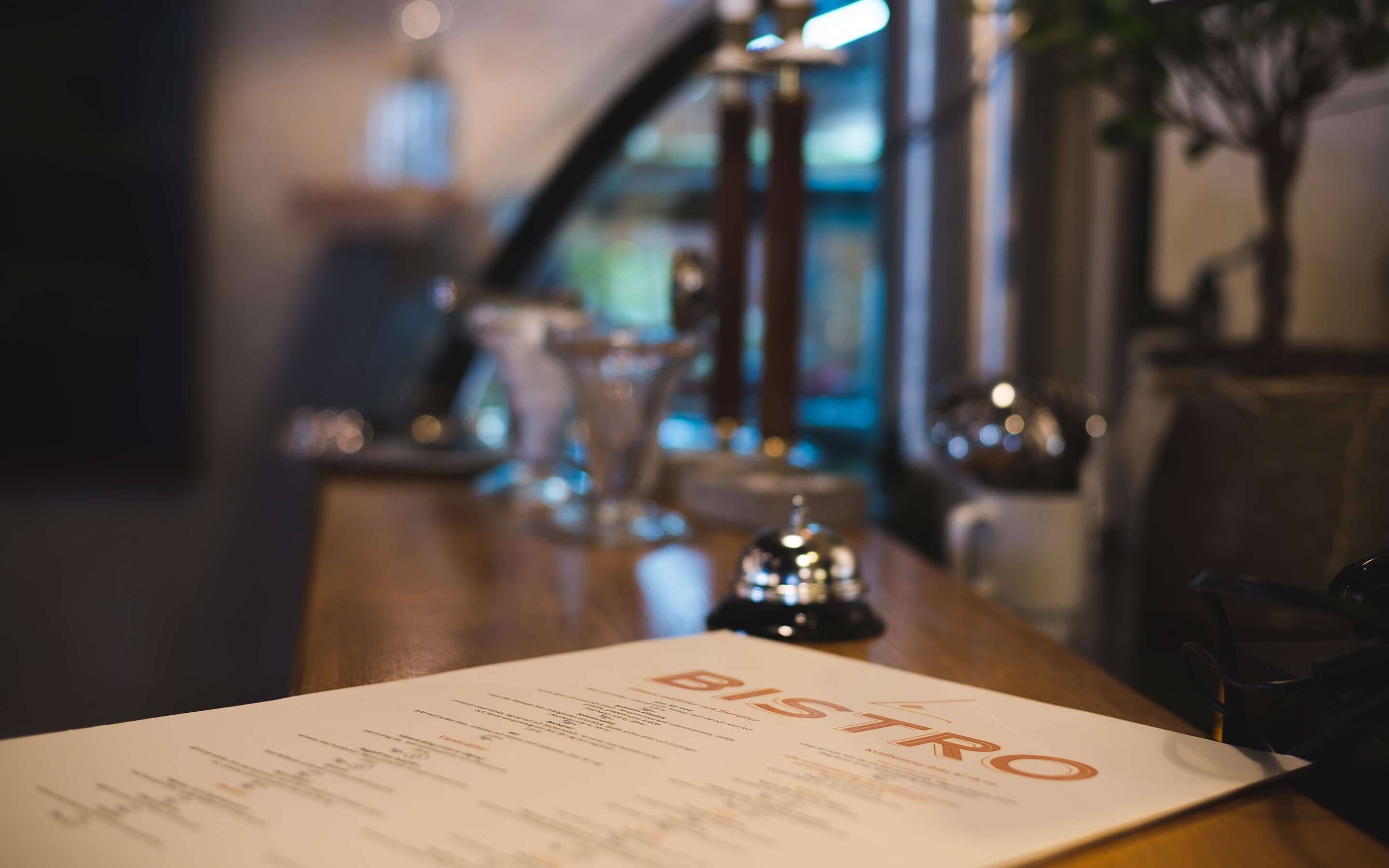 A menu titled "BISTRO" on a table in a dimly lit restaurant setting.