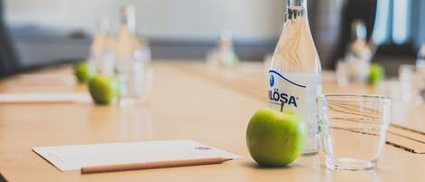 A table with a bottle of water, a glass, and an apple.